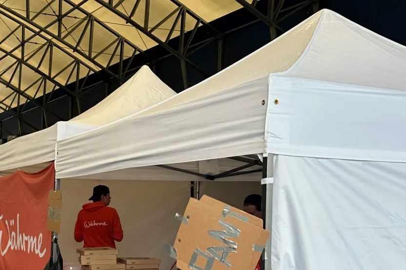 Währmes vita cateringtält i en stor hall, med pizzakartonger på disken och personal i Währme-tröja.